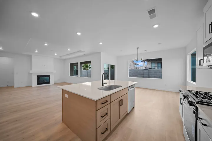 Open-concept living space featuring wood-finish flooring, recessed lighting, and a modern fireplace with a white shiplap-style surround