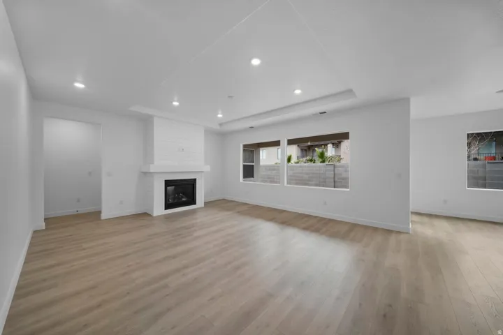 Recessed lighting, wood-finish flooring, fireplace with shiplap detail, and multiple windows