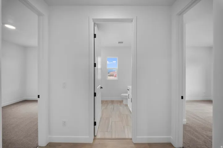 White interior walls, dark door hardware, and light wood-finish flooring