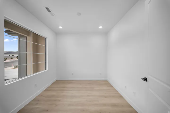 Recessed ceiling lighting, wood-finish flooring, and a large window with grid panes