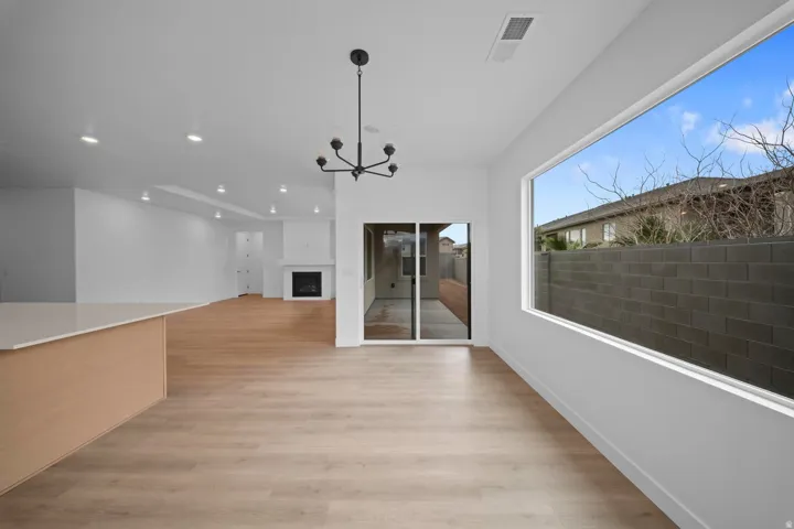 Expansive open concept living area featuring wood-finish flooring, a built-in fireplace, and a large horizontal window