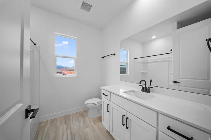 White vanity with built-in sink, black fixtures, and a large wall-mounted mirror