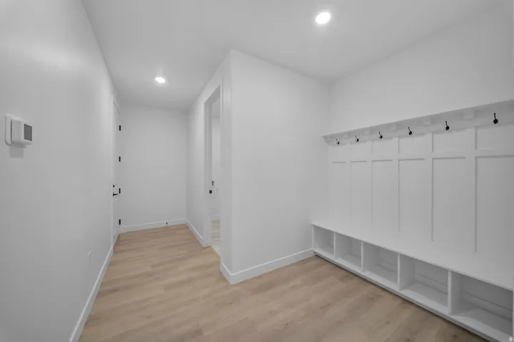 Entryway featuring light wood-finish flooring, recessed lighting, and a built-in bench with storage cubbies and coat hooks