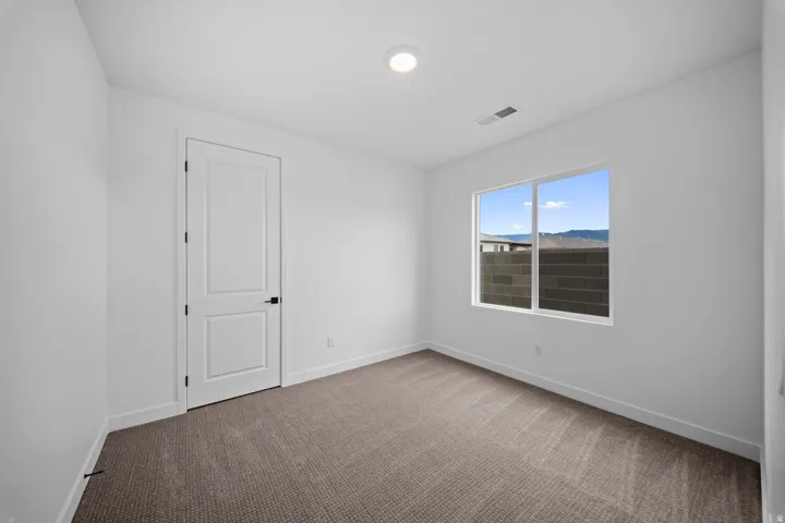 Recessed ceiling light, neutral tone walls, white trim, textured carpet flooring, and a single window