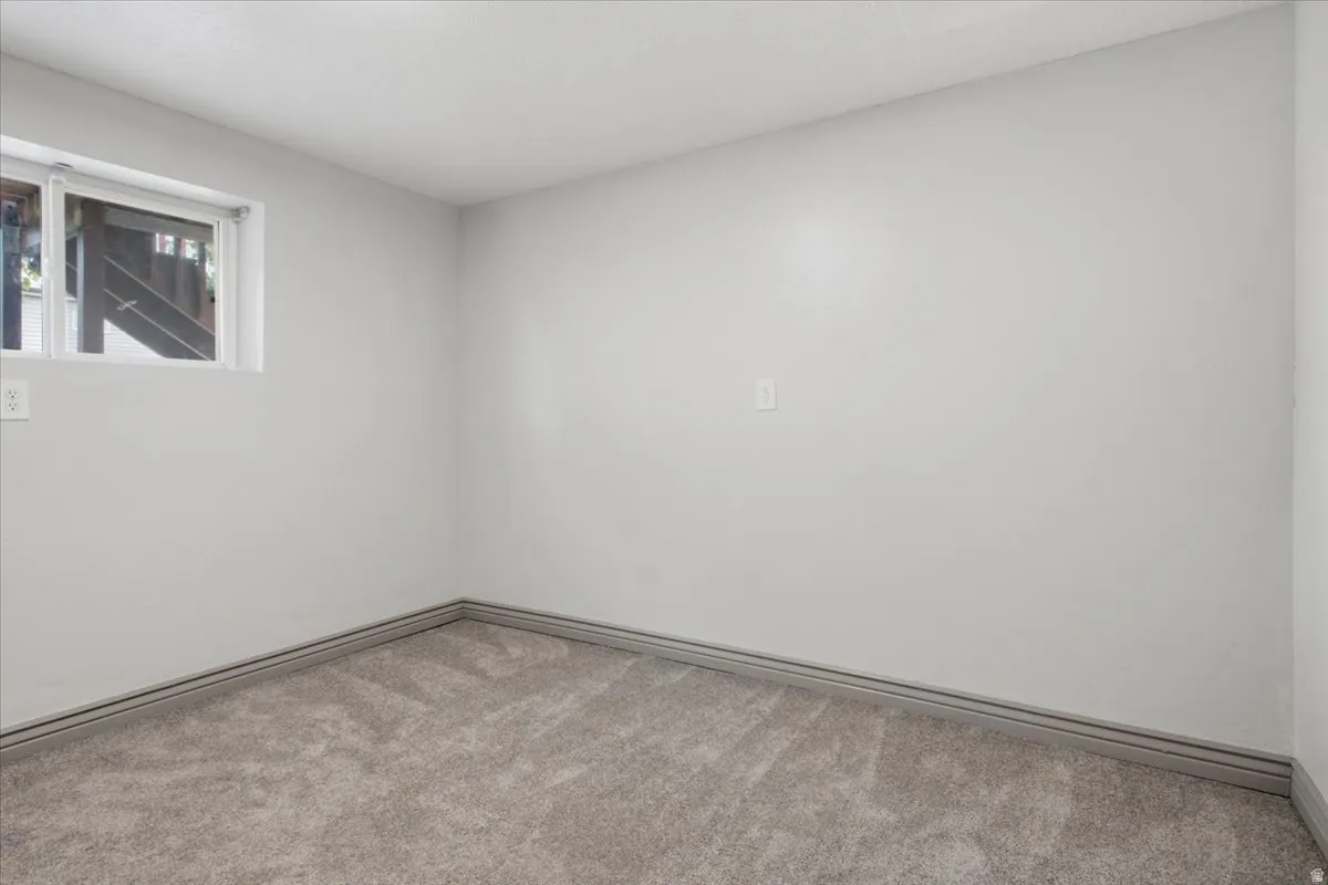 Textured carpeting, light gray wall paint, white trim, and a window providing natural illumination