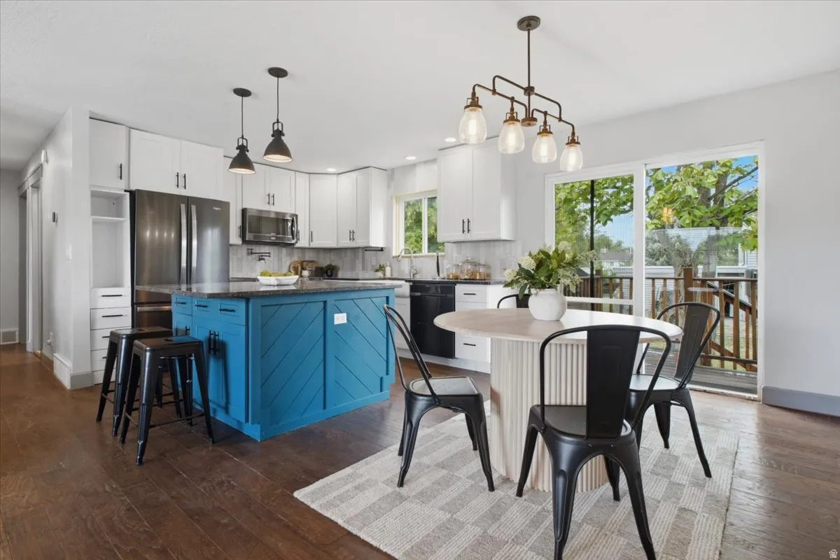 Kitchen featuring a blue island with a dark countertop, white cabinetry, and stainless steel appliances
