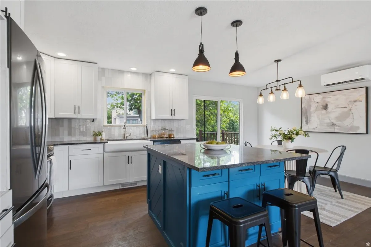 Kitchen featuring a blue island with granite countertop, white cabinetry, stainless steel appliances, and wood-finish flooring