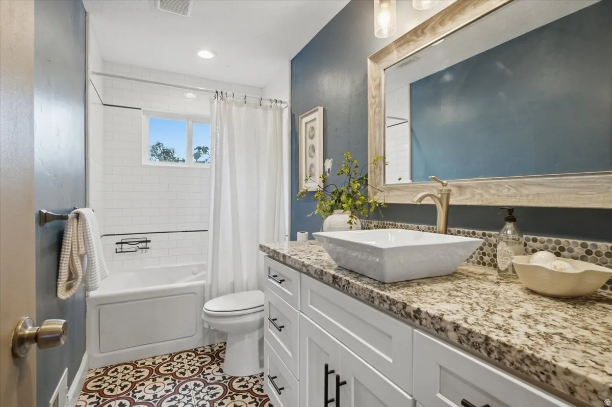 White vanity with granite countertop, vessel sink, and brushed nickel faucet