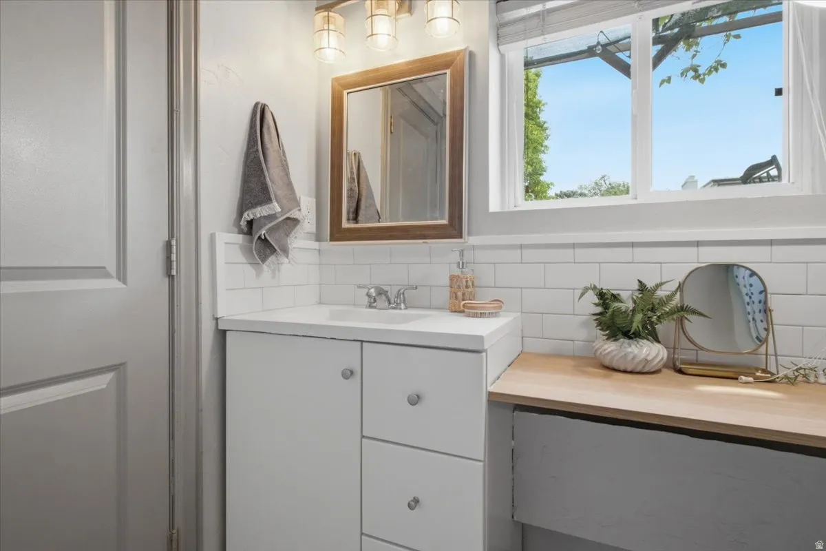 White vanity with integrated sink, wood-framed mirror, and a wall-mounted light fixture