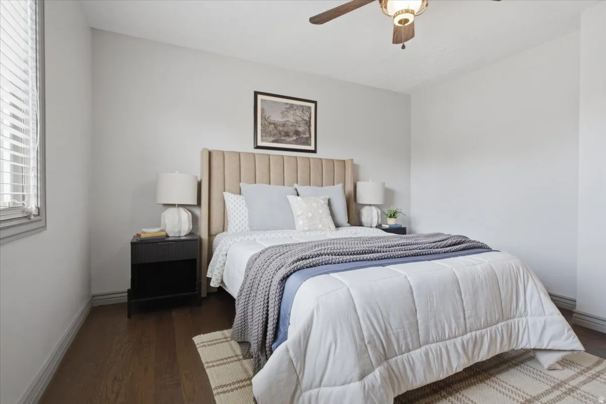 Wood-finish flooring, a ceiling fan with integrated lighting, and a window with blinds