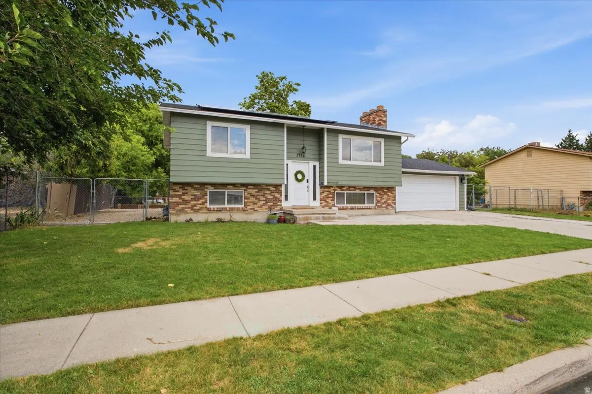 Split-level residence featuring green siding and brick veneer