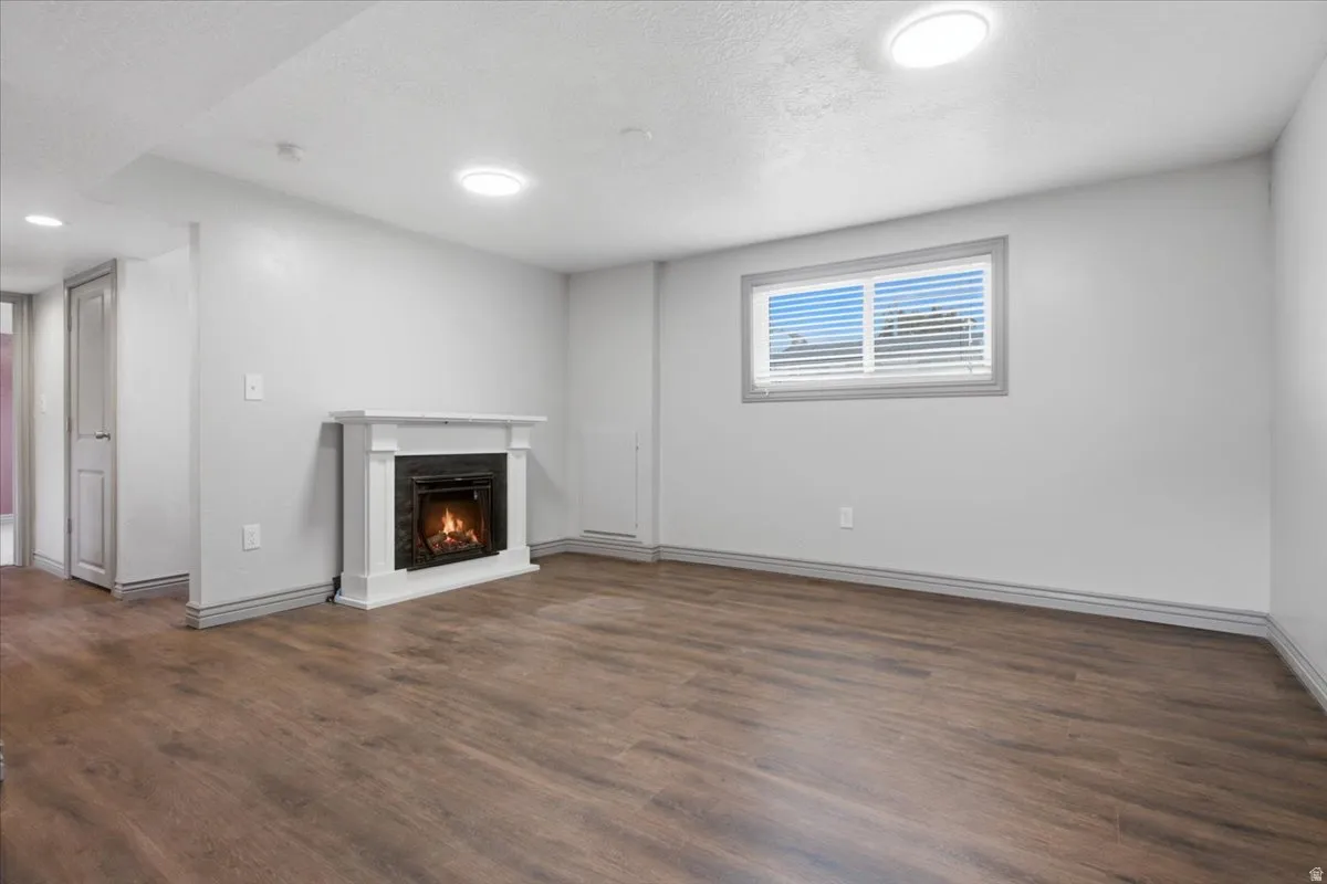 Wood-finish flooring, white walls, and a white fireplace with a dark surround