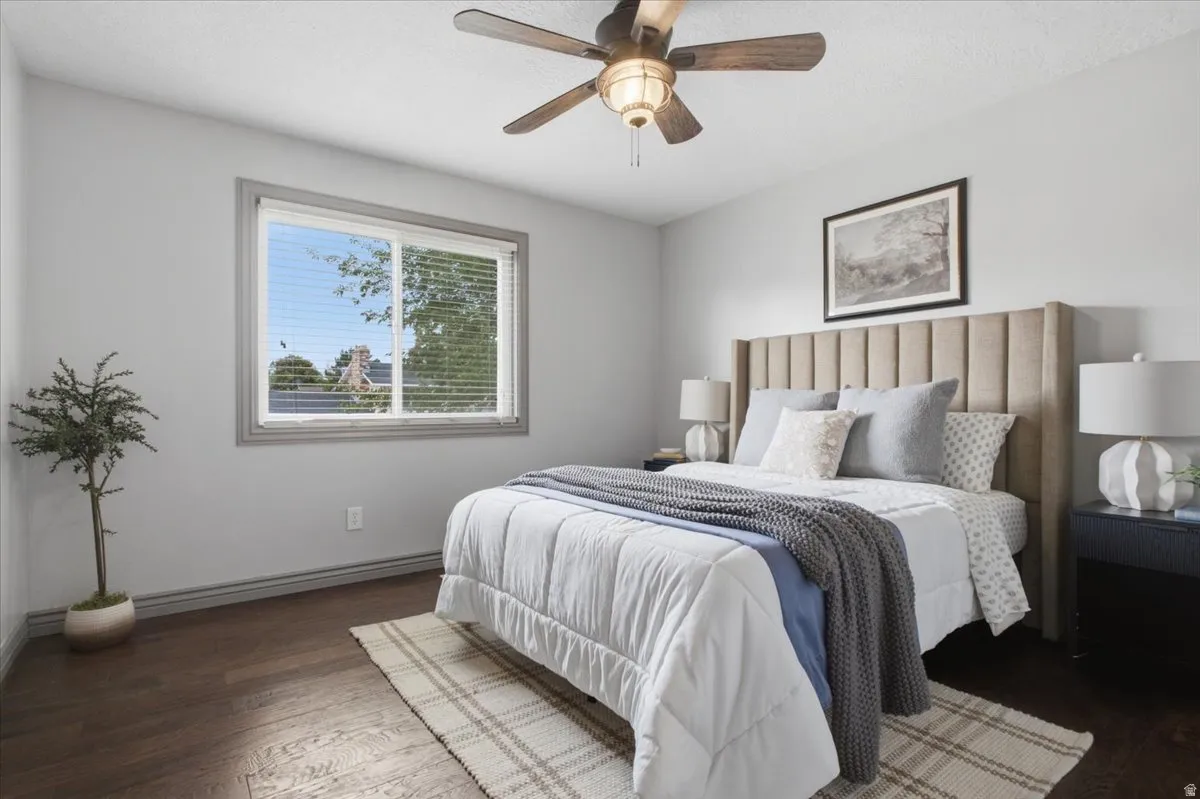 Wood-finish flooring with light gray walls, a ceiling fan with integrated lighting, and a large window with blinds