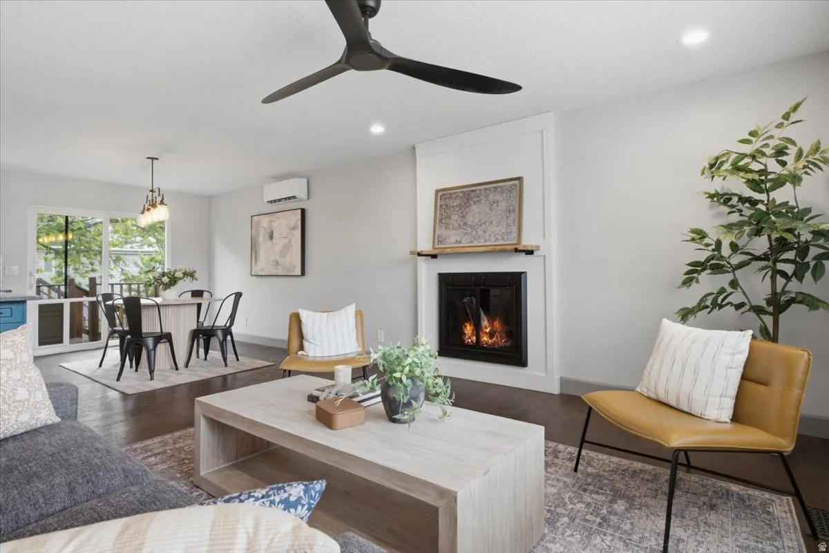 Living space featuring a fireplace with a wood mantle, wood-finish flooring, and a ceiling fan