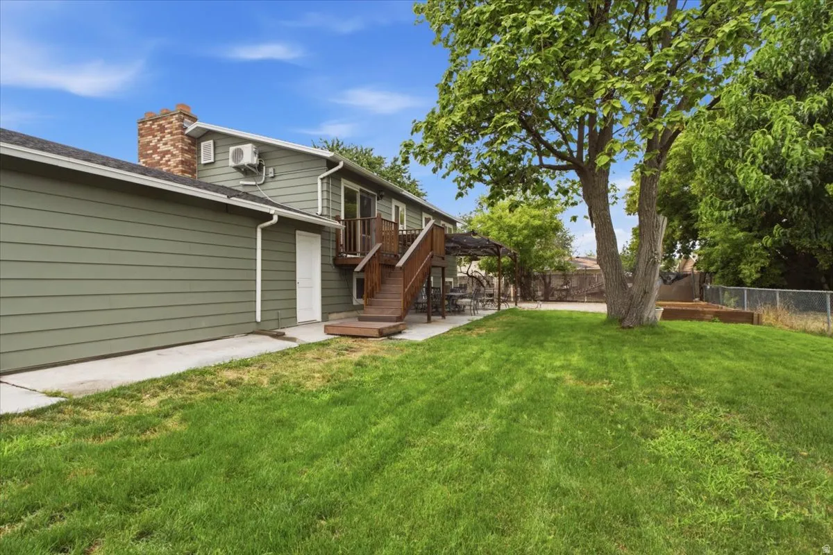 Expansive lawn with mature trees, a multi-level wood deck, and a raised garden bed