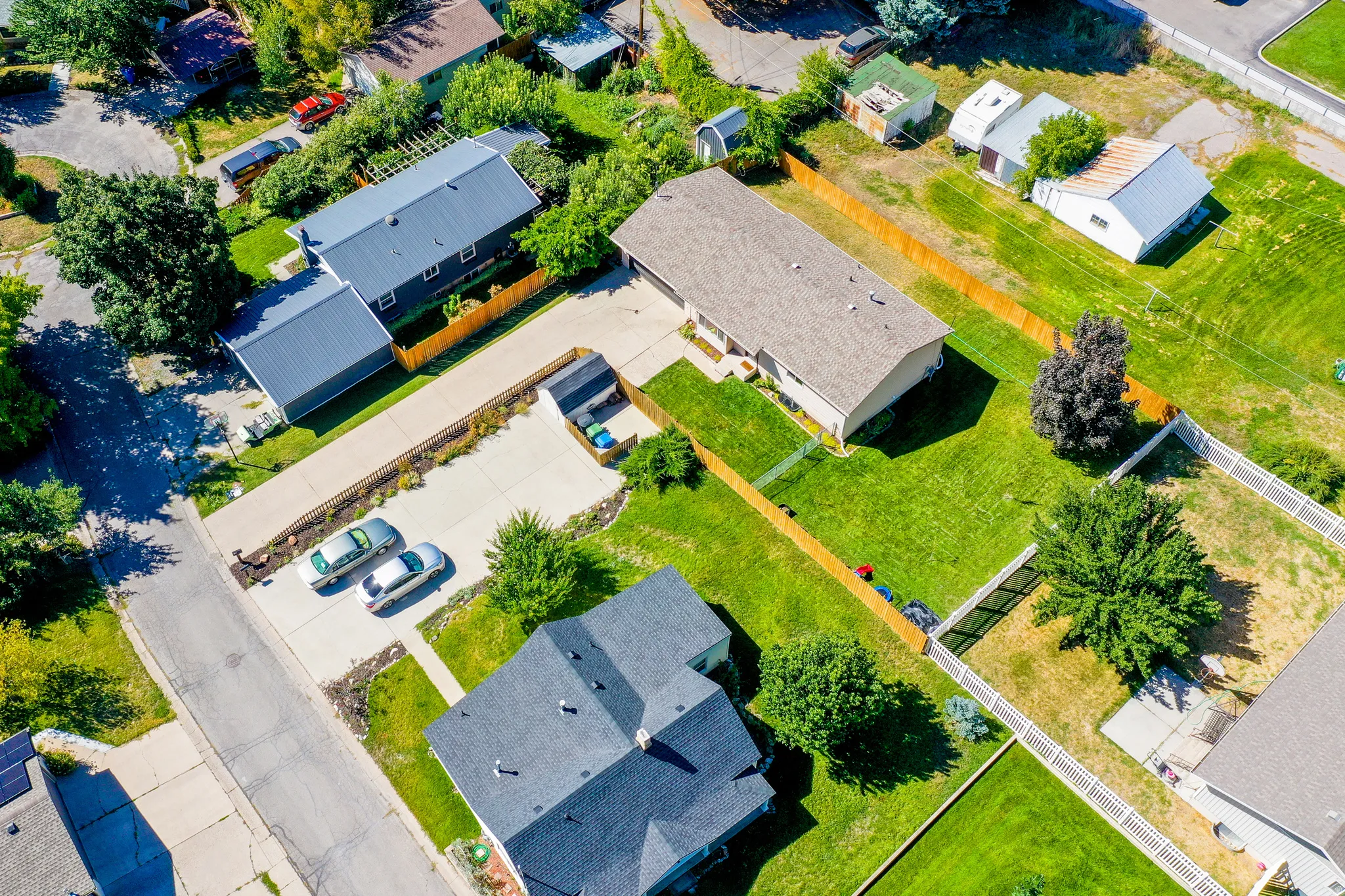 Expansive lot featuring two distinct structures, a large paved driveway, and mature landscaping