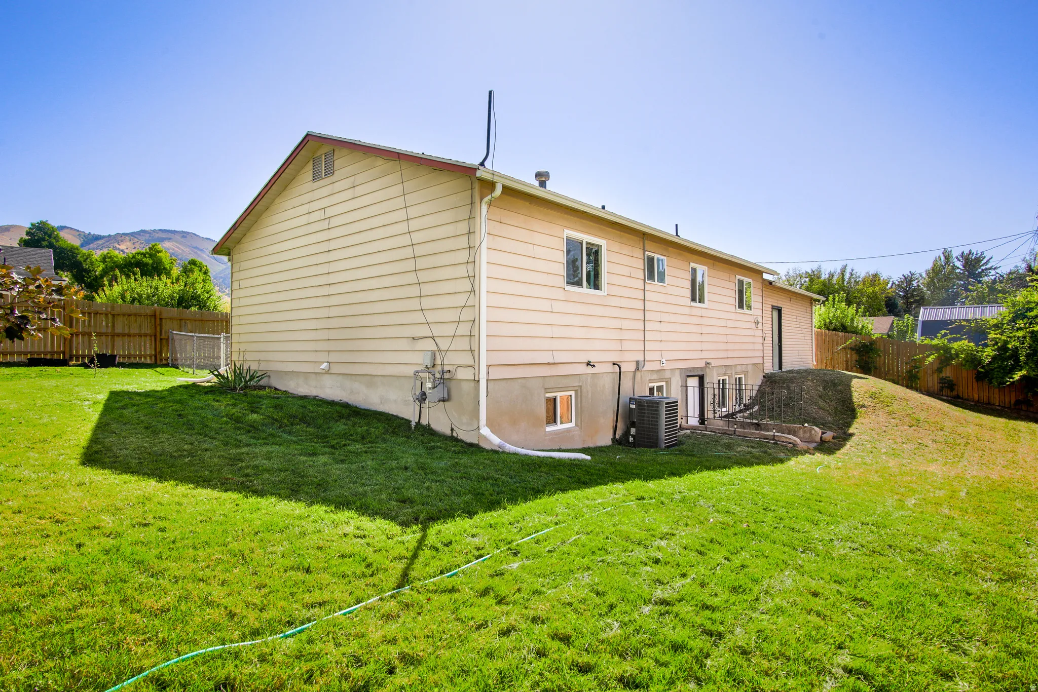 Expansive backyard with a manicured lawn, wood fencing, and mature landscaping