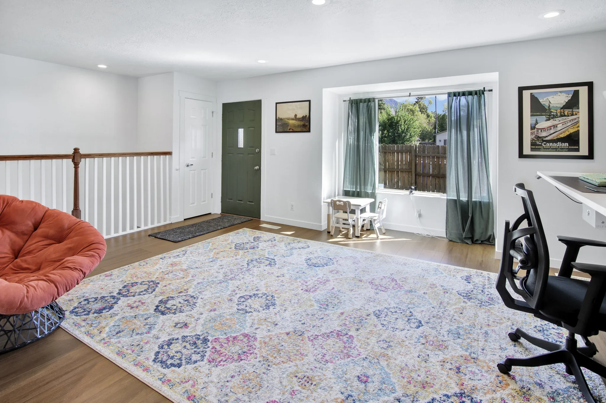 Bright open-concept living area featuring wood-finish flooring, recessed lighting, and a prominent bay window