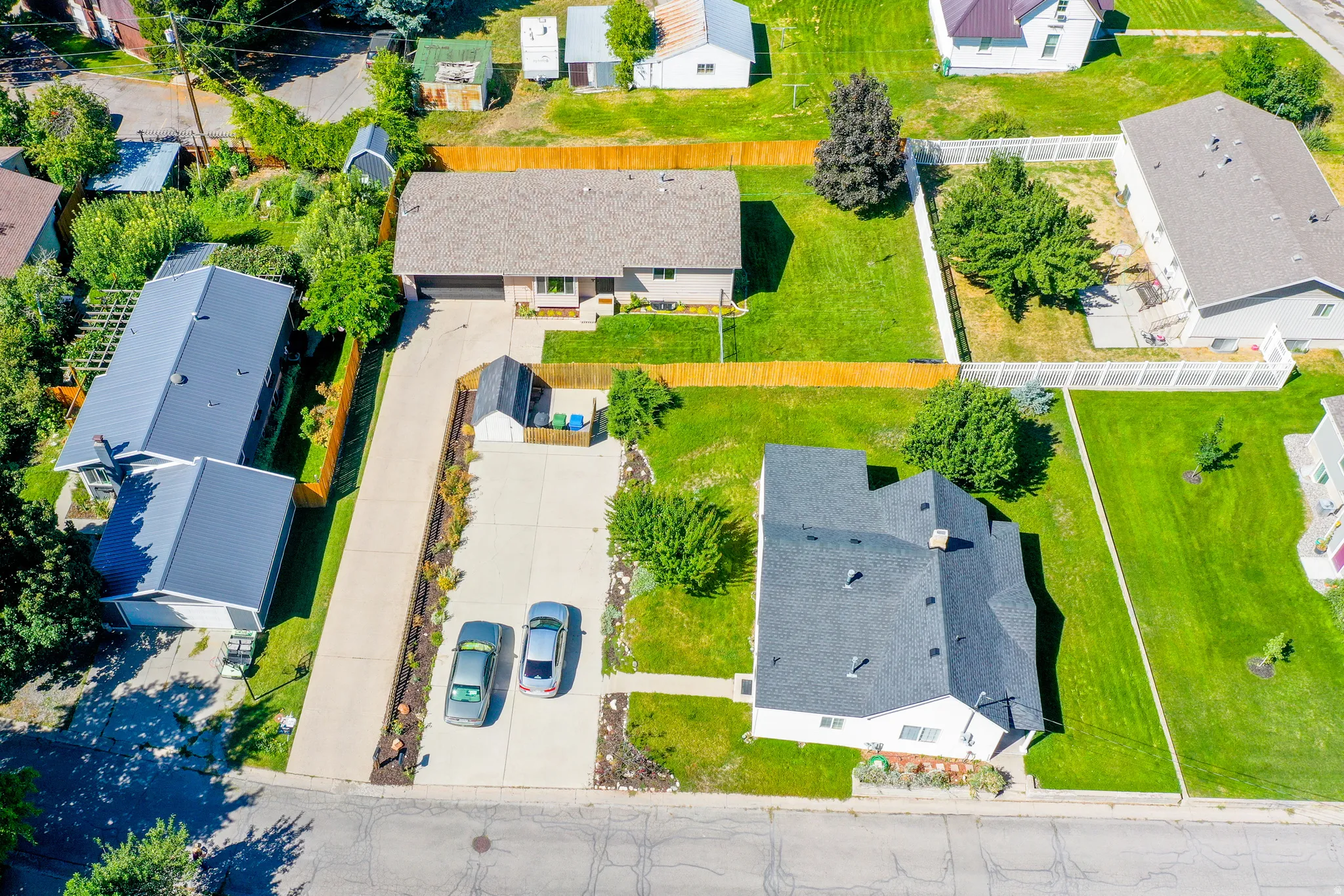 Two-car driveway, attached garage, manicured lawn, and perimeter fencing
