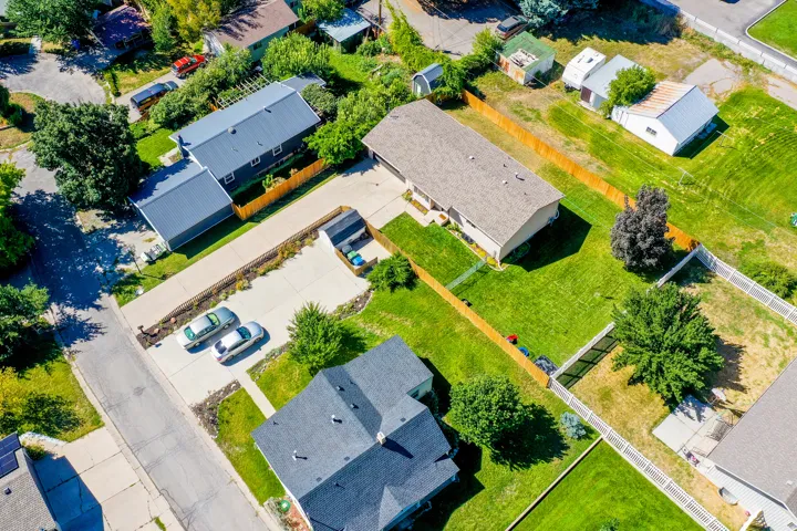 Expansive lot featuring two distinct structures, a large paved driveway, and mature landscaping