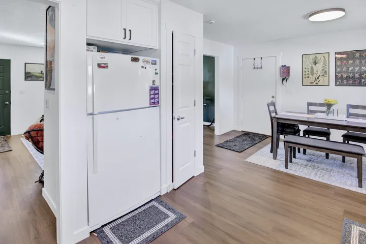 Wood-finish flooring throughout, white upper cabinetry, and a built-in refrigerator