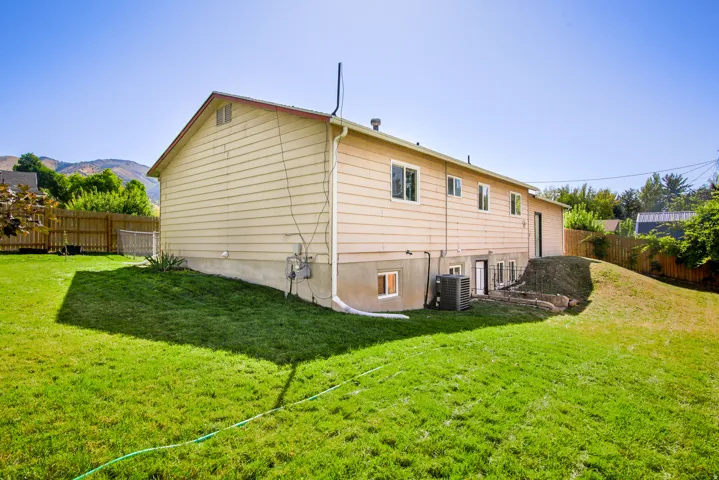 Expansive backyard with a manicured lawn, wood fencing, and mature landscaping