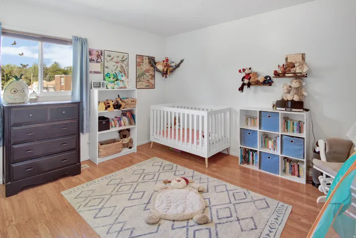 Wood-finish flooring, white walls, and a window with a light-colored curtain