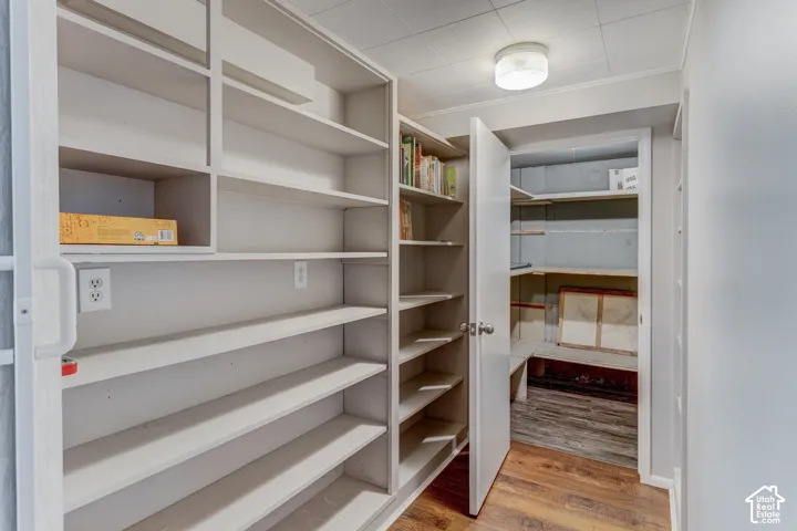 Built-in shelving, wood-finish flooring, recessed lighting, white interior door, and wall-mounted electrical outlets