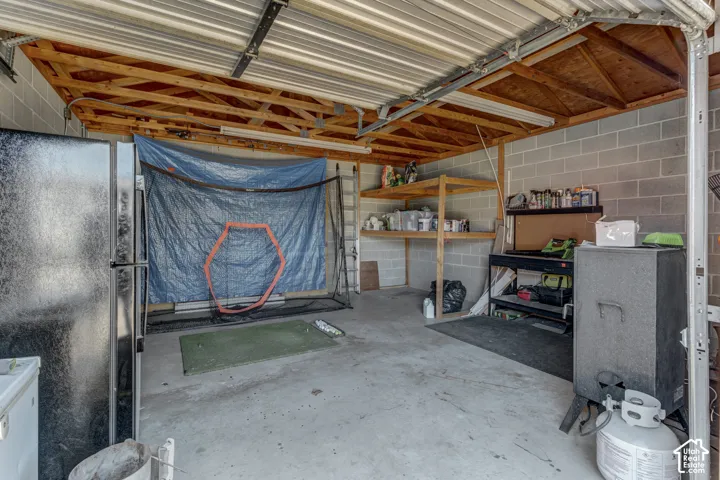 Concrete flooring with exposed wood beam ceiling, block wall construction, and built-in shelving