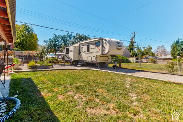 Expansive backyard featuring a gravel driveway, chain-link fencing, and raised garden beds