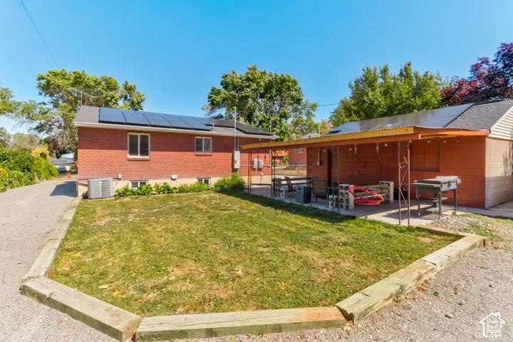 Brick exterior with solar panels, ground-level windows, and a covered patio