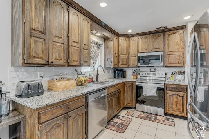 Wood-finish cabinetry, stainless steel appliances, granite countertops, tile flooring, and a subway tile backsplash