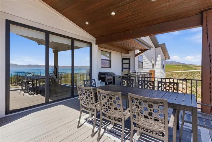 Covered outdoor deck with expansive water scenery, large sliding glass doors, composite decking, and a contemporary railing design