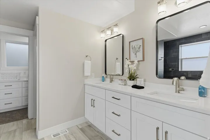 Dual vanity with white cabinetry and integrated sinks, complemented by contemporary mirrors and brushed nickel fixtures