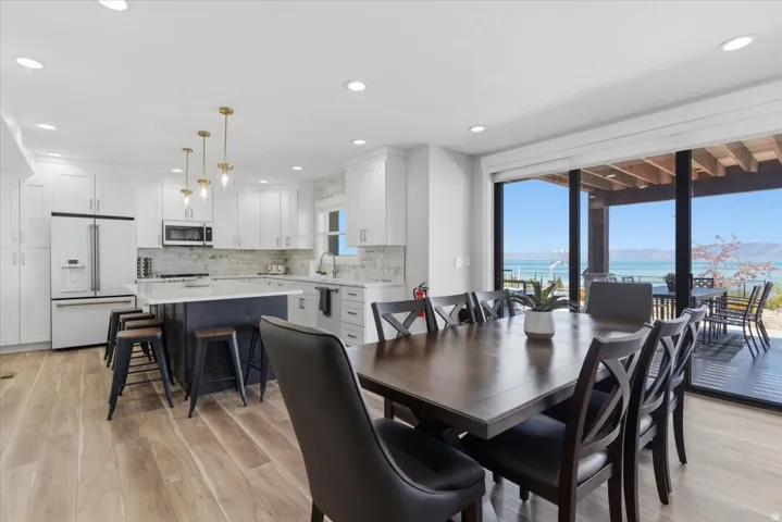 Open-concept kitchen and dining area featuring wood-finish flooring, white cabinetry, a kitchen island with seating, and a full suite of stainless steel appliances