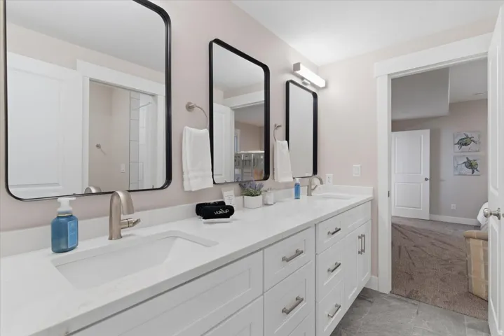 Dual vanity with integrated sinks, white cabinetry, brushed nickel hardware, and rectangular mirrors with black frames
