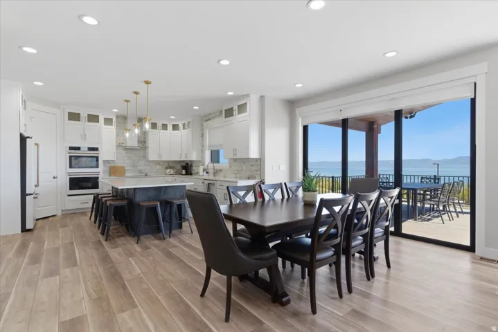 Open-concept kitchen and dining area featuring light wood-finish flooring, white cabinetry, a central island with countertop seating, and built-in stainless steel appliances