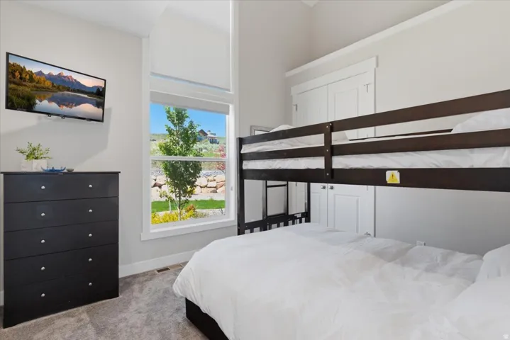Vaulted ceiling, wall-mounted television, large window, bunk bed, and built-in cabinetry