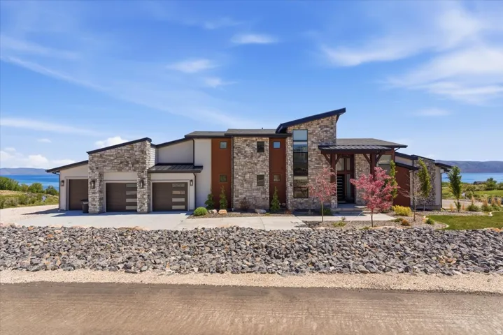 Contemporary exterior with stone accents, a three-car garage, and a prominent covered entry