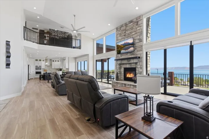 Stone-clad fireplace with a wood mantel, wood-finish flooring, and expansive windows