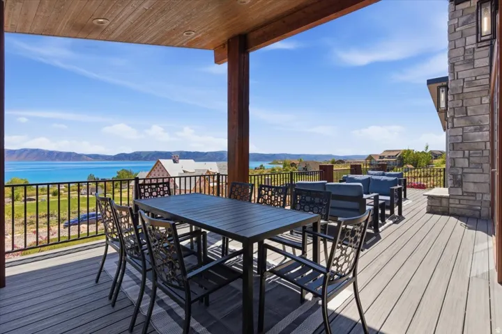 Expansive covered deck featuring composite decking, wood-plank ceiling, and stone-clad exterior elements