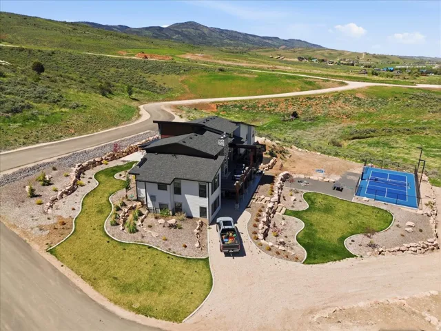 Contemporary residence with a dark-pitched roof, multi-level decks, and an outdoor sport court