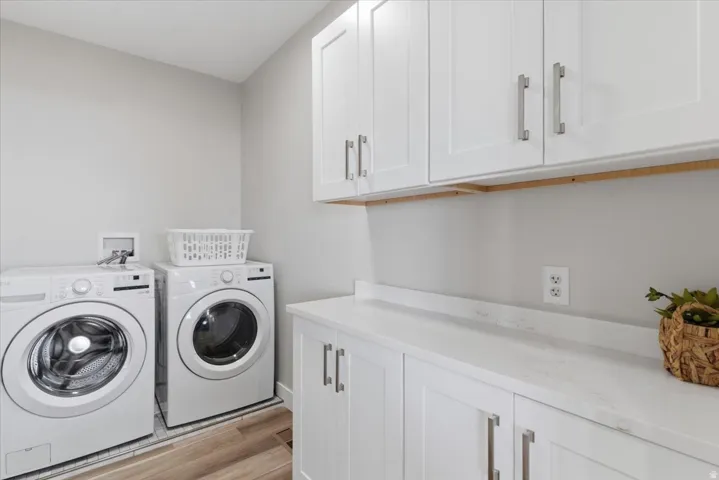 White shaker cabinetry with brushed nickel hardware, white countertop, wood-finish flooring, and light gray wall paint