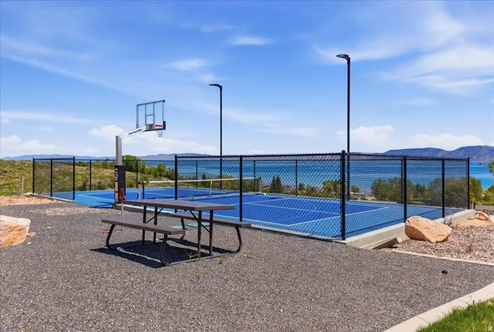 Multi-sport court with basketball hoop, chain-link fencing, and overhead lighting