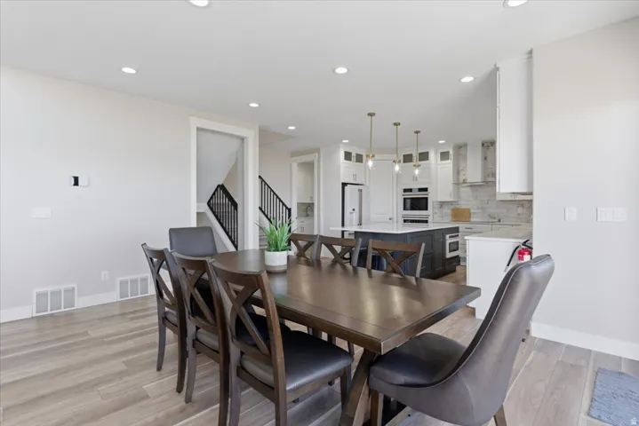 Recessed lighting, wood-finish flooring, white cabinetry, kitchen island with built-in microwave, and stainless steel appliances