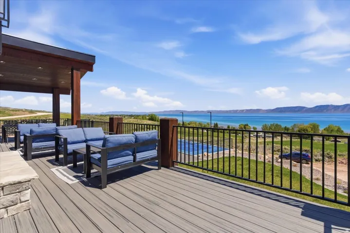 Expansive composite deck with a covered outdoor area, black metal railing, and distant water scenery