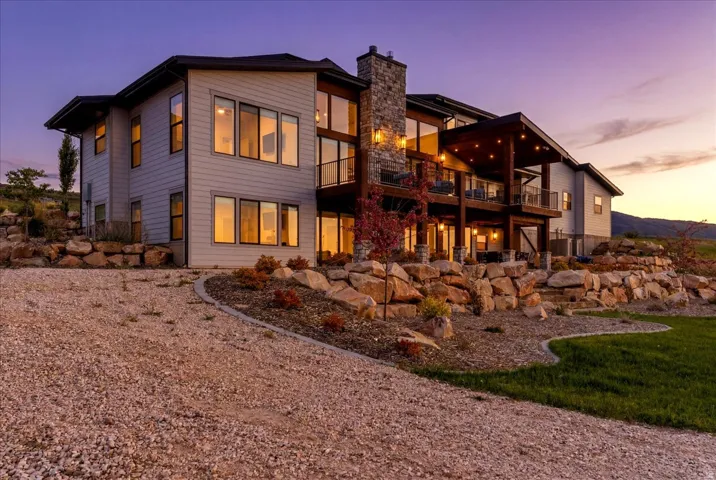 Multi-level residence featuring extensive glass panels, a stone chimney, and a multi-tiered balcony