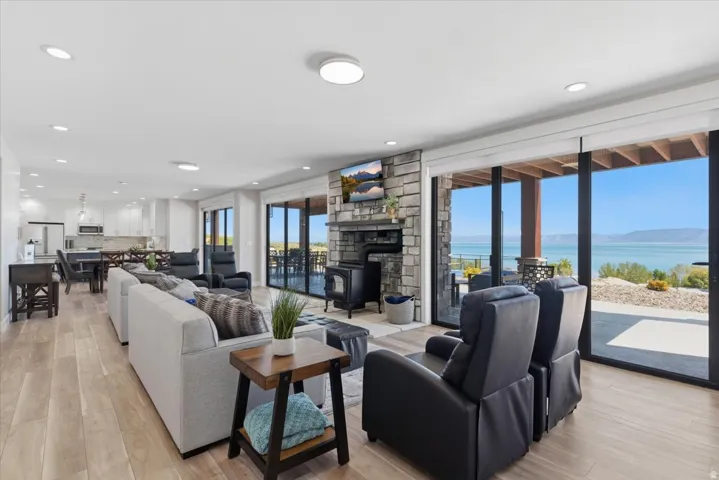 Open-concept living space with wood-finish flooring, a stone-faced fireplace, and recessed lighting
