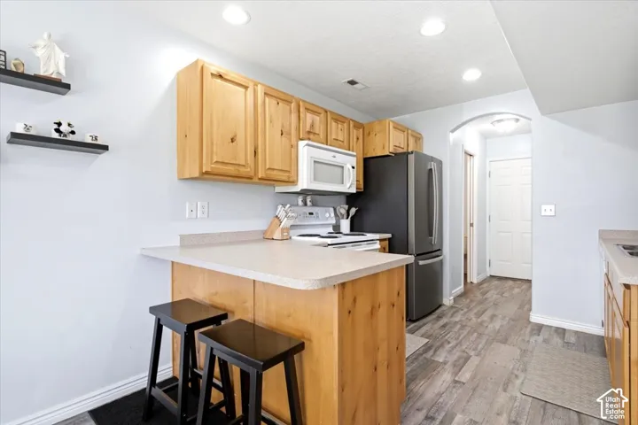 Kitchen featuring wood-finish cabinetry, light-toned countertops, and stainless steel appliances