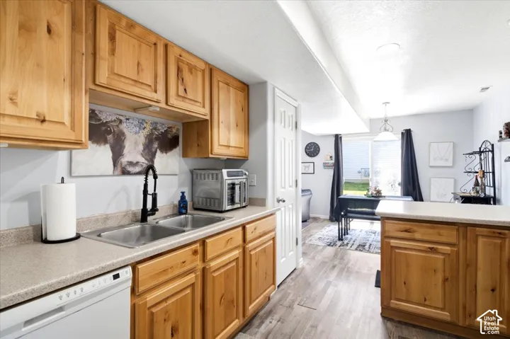 Kitchen featuring wood-finish cabinetry, a double basin stainless steel sink with a matte black faucet, and light-toned countertops